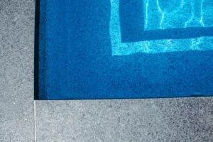 Detail close-up of the inground pool corner showing blue pebble aggregate vinyl liner and dark grey coping edge - Mississauga pool installation by Destination Pools and Landscaping